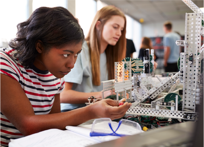 Students building and examining a robotics structure in a classroom