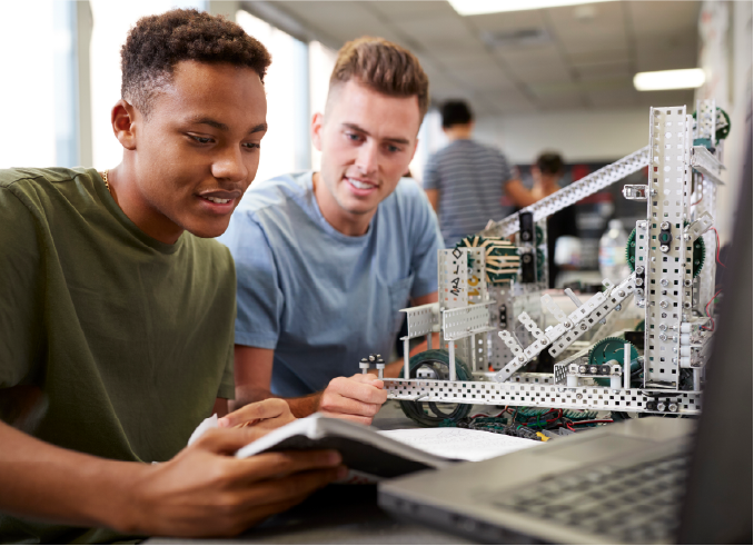 Two students reviewing a robotics build together in a lab
